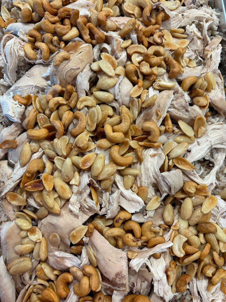 Catering platter topped with shredded chicken and nuts